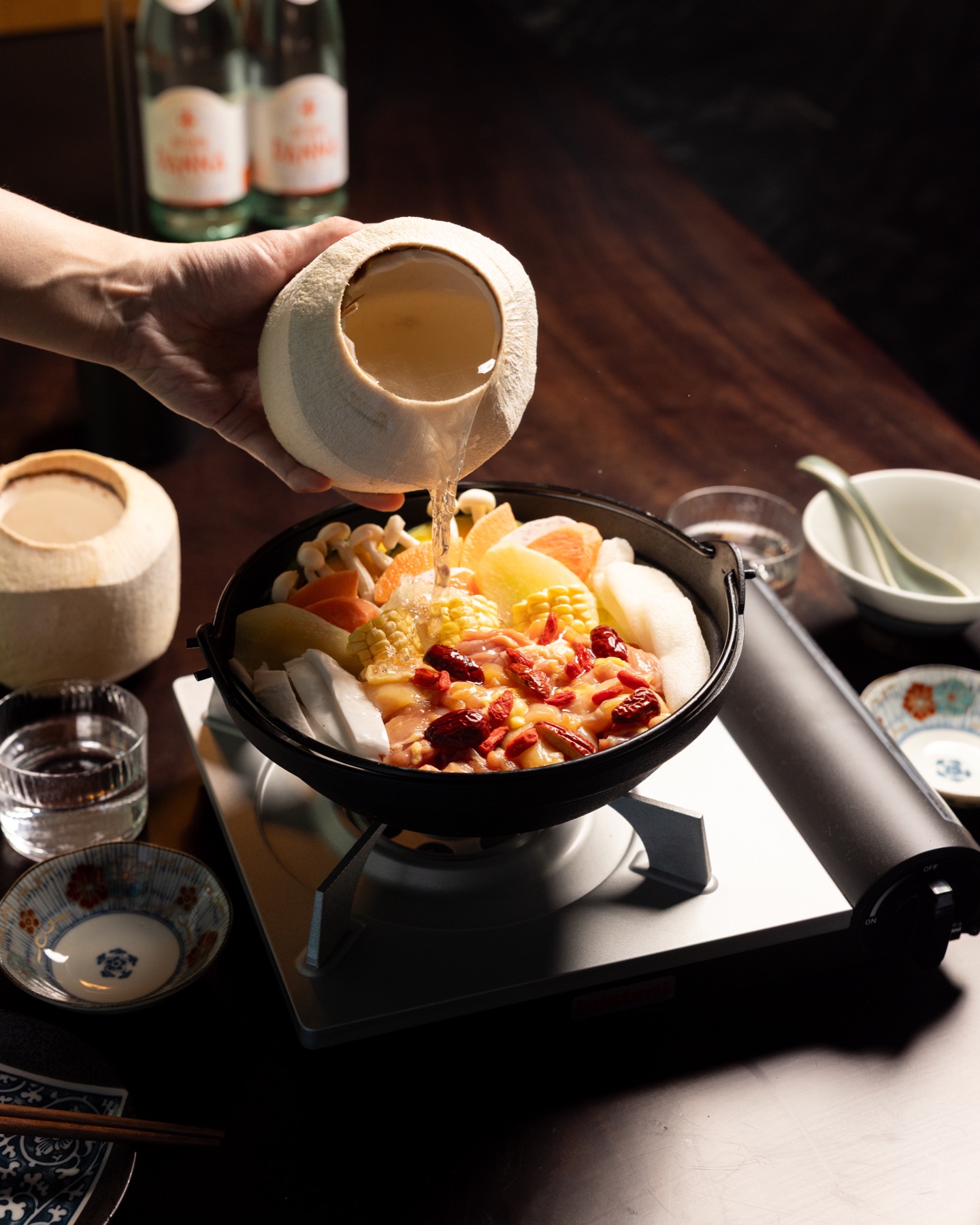Coconut water being poured into chicken nabe